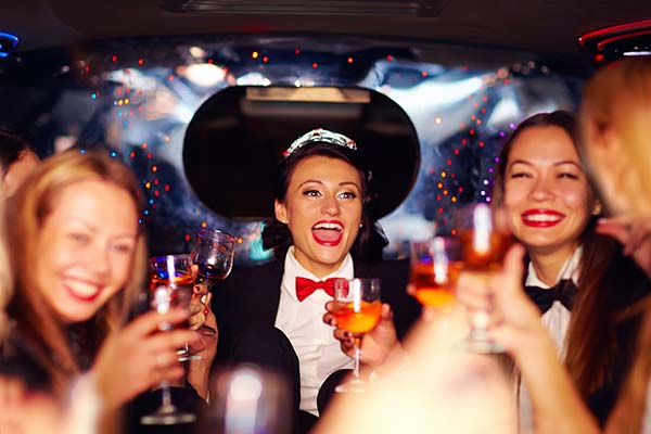 Group of happy elegant women clinking glasses in limousine, going to a birthday party